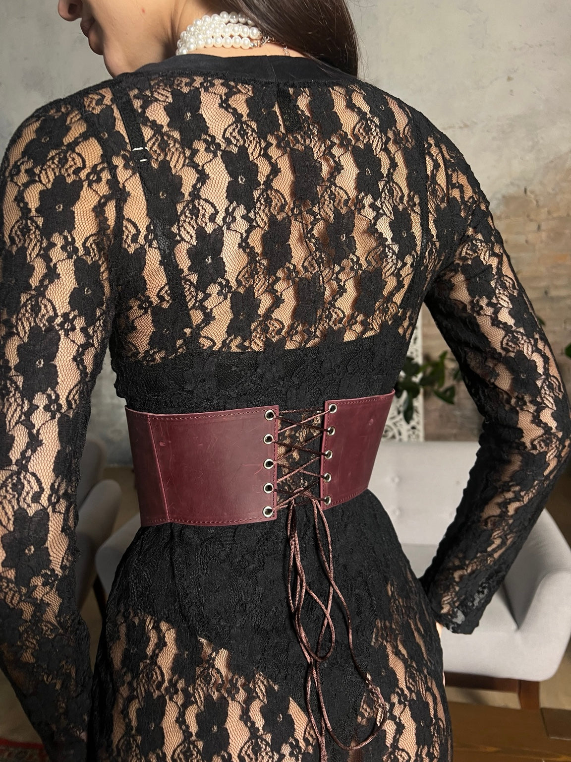 Close-up burgundy long leather underbust corset over black lace