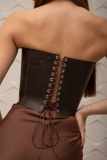 the back of a woman wearing a brown leather corset with a lace-up detail.