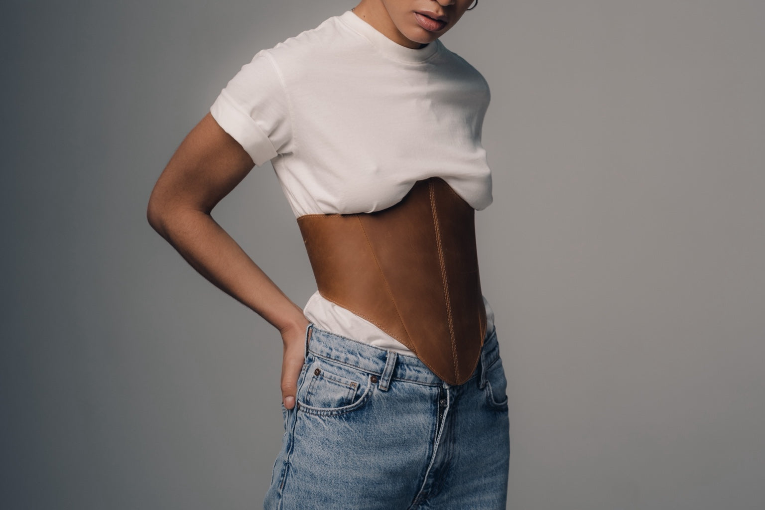 Side styling with beige long leather underbust corset belt and jeans